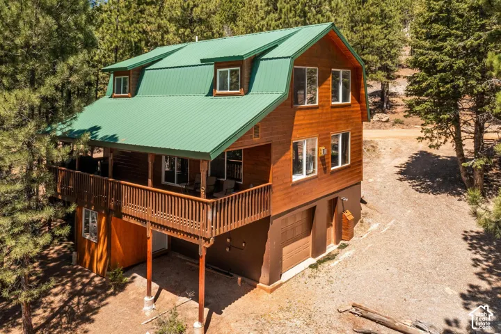 Wooden exterior with a green metal roof, multiple windows, and a wrap-around balcony