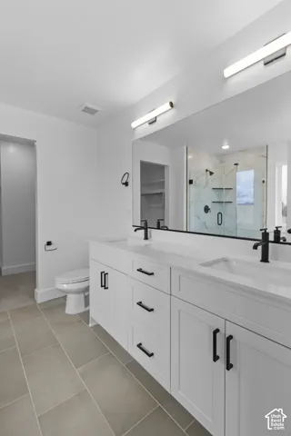 Dual vanity with undermount sinks and matte black fixtures, white shaker cabinetry with black hardware, large mirror, and tiled flooring