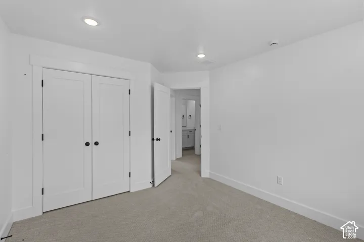 Recessed lighting, painted white trim, white paneled doors with black hardware, and gray carpet flooring
