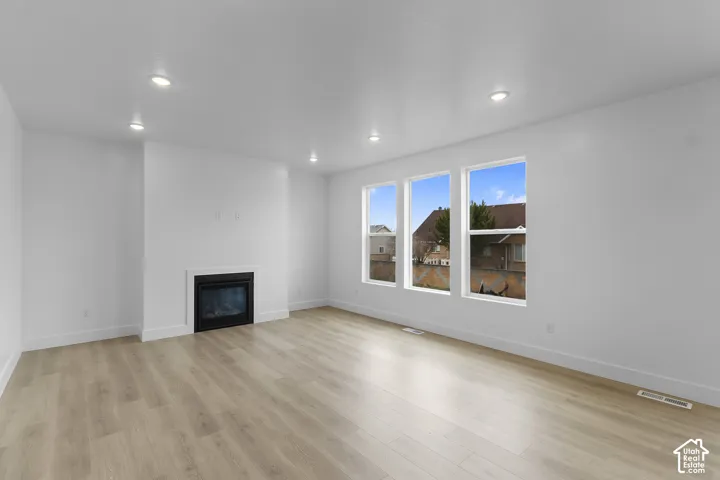 Spacious room featuring wood-finish flooring, recessed lighting, and an integrated fireplace