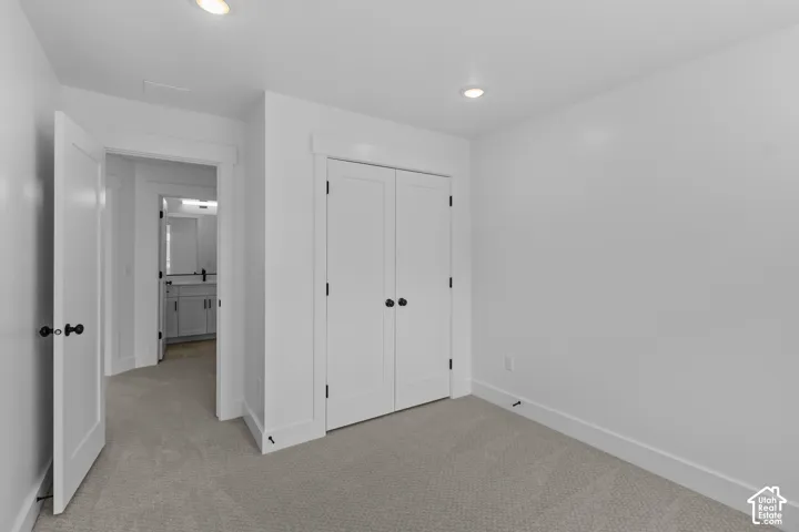 Recessed ceiling lighting, light-toned carpeting, white interior doors with dark hardware, and white trim