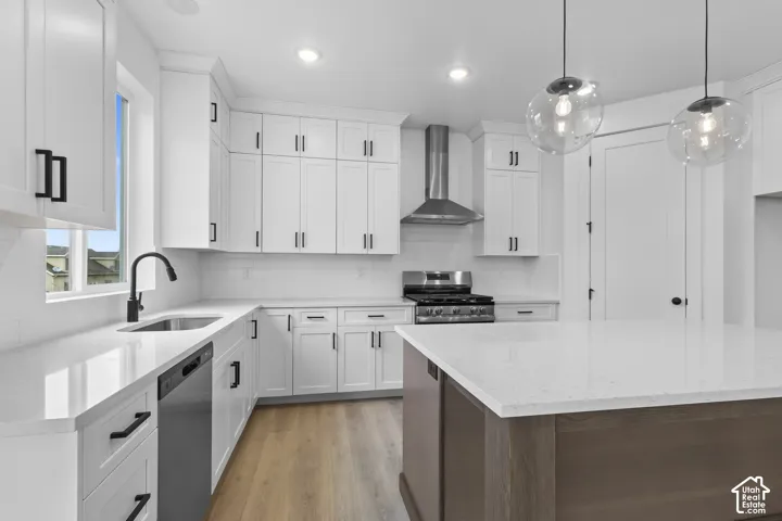 White shaker-style cabinetry with matte black hardware, stainless steel appliances, a center island with a light-toned countertop, and wood-finish flooring