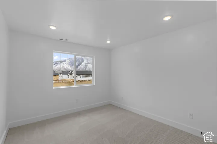Recessed ceiling lighting, white walls, light-toned carpet flooring, and a window with mountain scenery