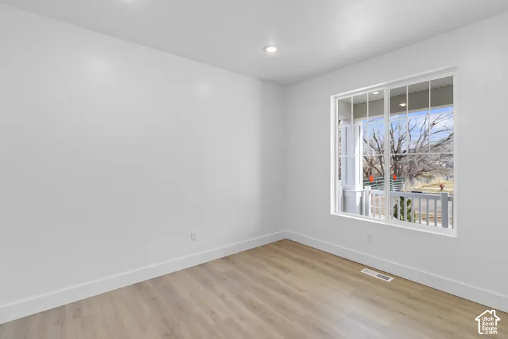 Recessed lighting, light wood-finish flooring, white walls, white trim, and a multi-pane window