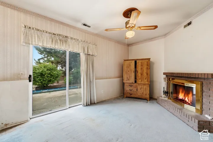 Brick fireplace with brass accents, glass sliding door, and a ceiling fan