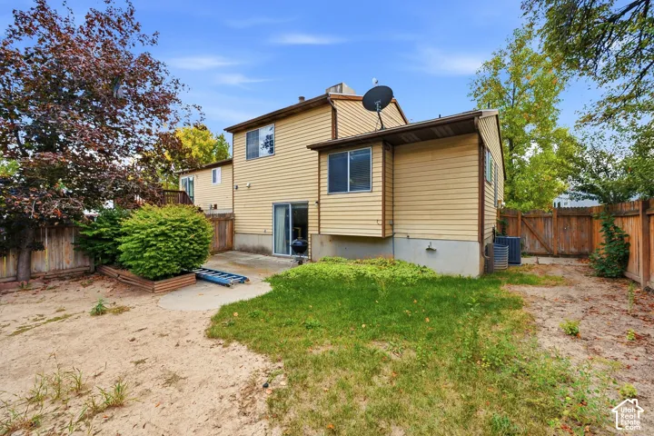 Rear exterior featuring horizontal siding, a sliding glass door, a concrete patio, and a wood-panel fence
