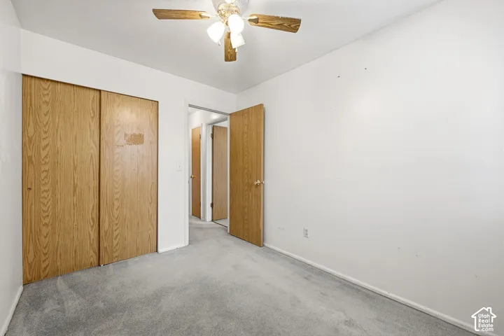 Light gray carpeting with white walls, featuring a ceiling fan with light fixture