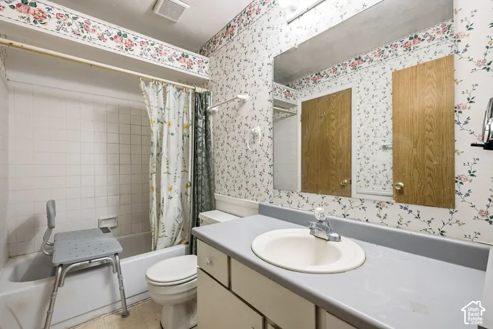 Bathroom featuring a vanity with a drop-in sink, a wall-mounted mirror, and a built-in tub with tile surround
