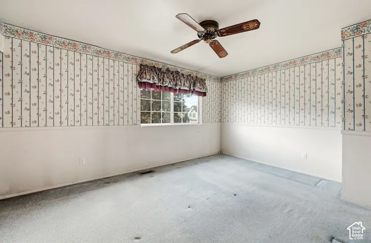 Wall-to-wall carpeting, ceiling fan, and window with exterior exposure