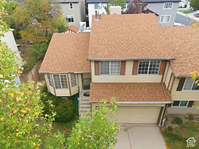 Two-story residence featuring a shingle roof, bay window, and attached garage