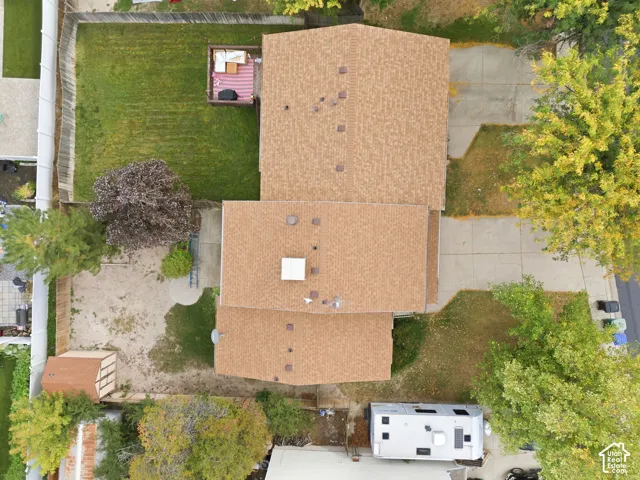 Gable roof with asphalt shingles, expansive paved driveway, rear wood deck, and a detached storage shed