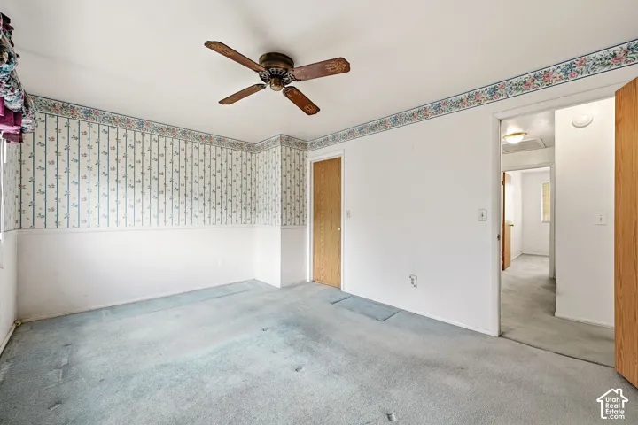 Carpeted room with a ceiling fan, a paneled door, and an open doorway