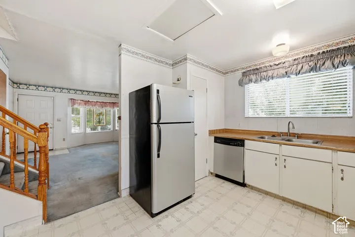 Kitchen featuring white cabinetry, a double basin stainless steel sink, and wood-finish countertops