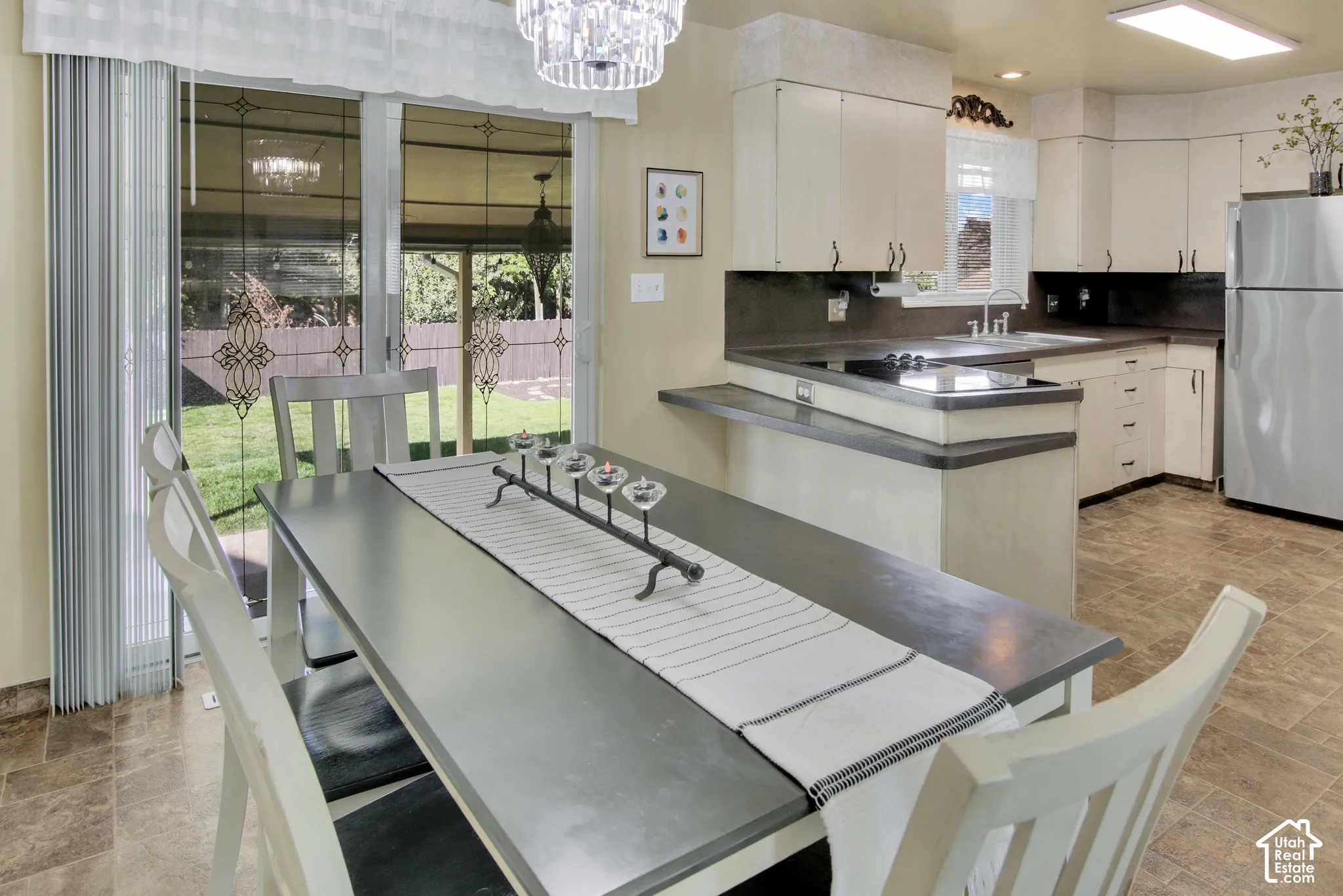 Kitchen featuring white cabinetry, dark countertops, and a stainless steel refrigerator. Sliding glass doors out to backyard