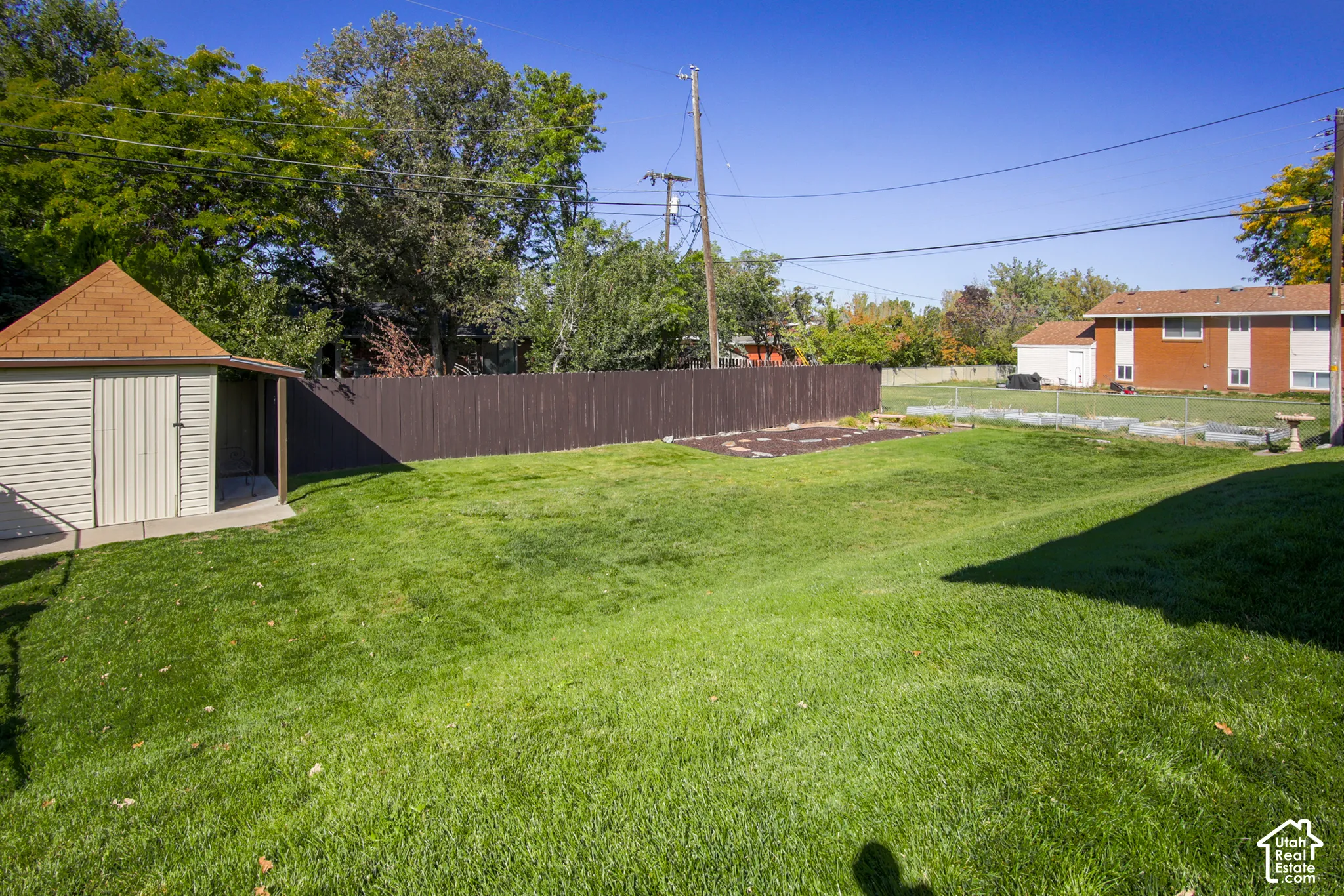 Expansive green lawn, storage shed with shingle roof, concrete patio, and privacy fencing