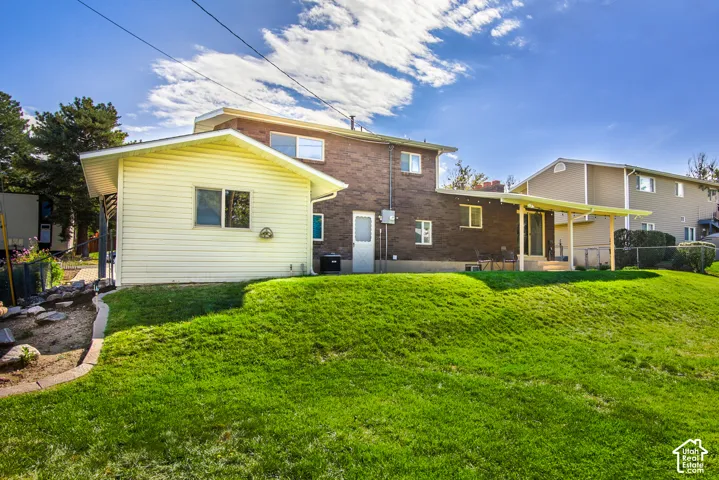 Expansive rear yard with a manicured lawn, brick exterior, covered patio, and a separate storage shed