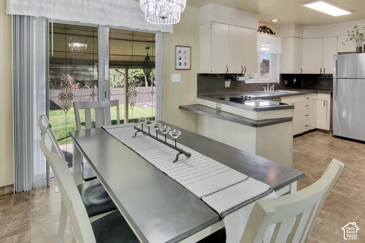 Kitchen featuring white cabinetry, dark countertops, and a stainless steel refrigerator. Sliding glass doors out to backyard