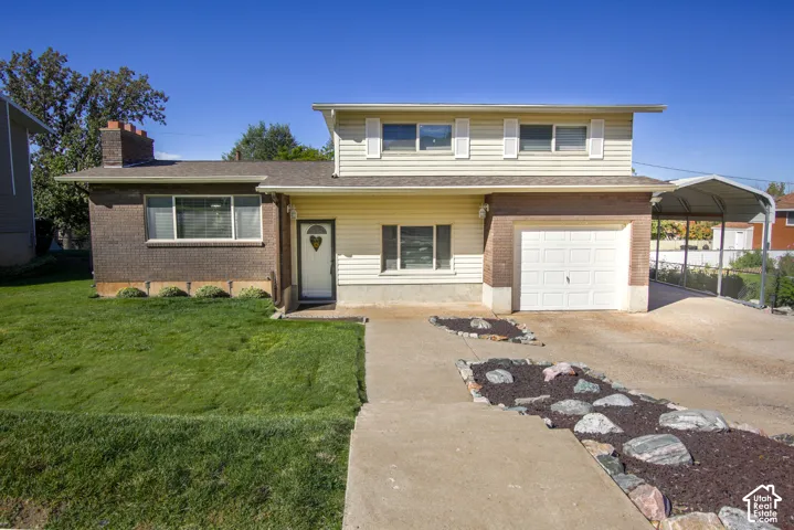 Two-story residence featuring a brick and siding exterior, an attached single-car garage, and a separate carport