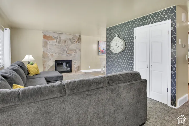 Stone-clad fireplace with black insert, patterned accent wall, and neutral wall and coat closet
