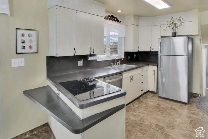 Kitchen featuring an electric cooktop, double basin sink, stainless steel refrigerator, and wood-vinyl flooring