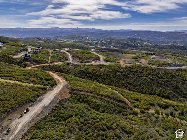Expansive hillside terrain featuring varied vegetation and distant mountain ranges
