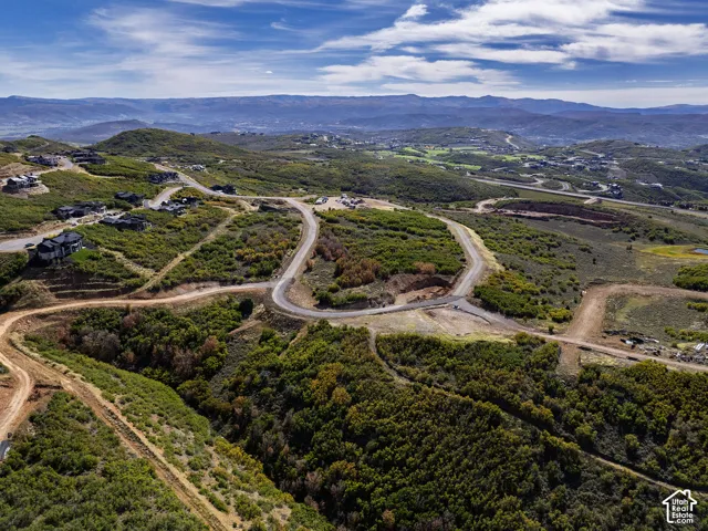 Expansive mountainous terrain with established roads, visible homes, and distant mountain ranges