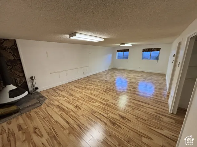 Spacious room featuring wood-finish flooring, a stone accent wall, and multiple windows