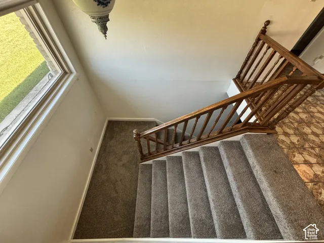 Staircase featuring wood railings, carpeted treads, and a decorative ceiling light fixture