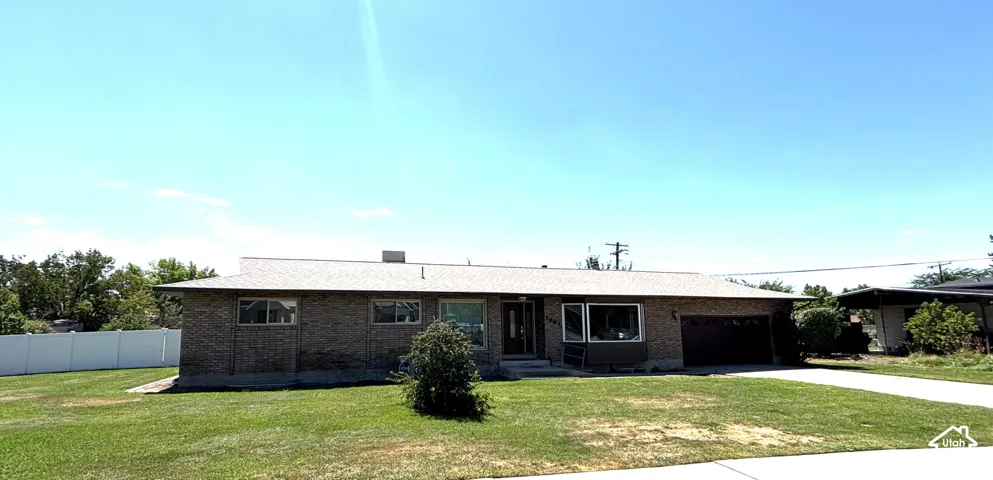 Brick exterior residence featuring a front lawn and an attached single-car garage