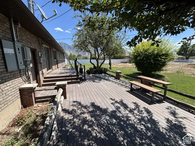 Expansive exterior deck with wood-finish planks, brick accents, and direct access to a grassy yard