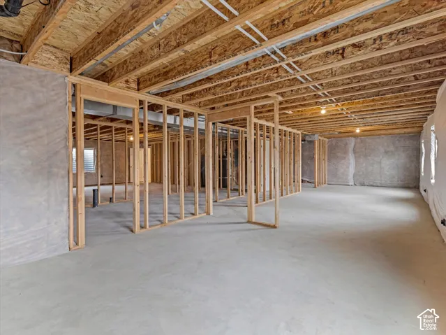 Unfinished lower level with wood framing, concrete flooring, and exposed ceiling joists