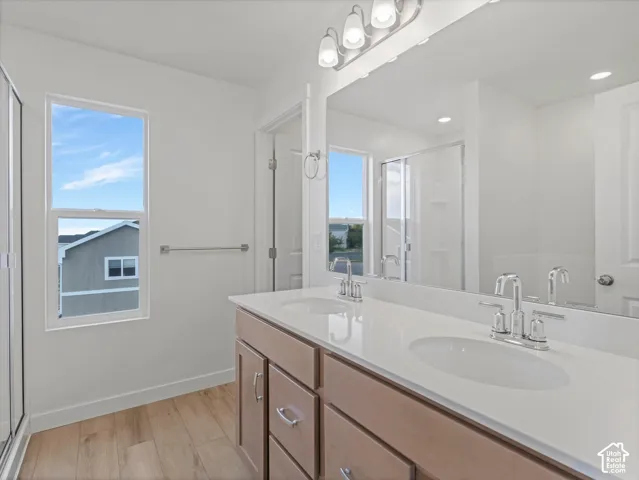 Bathroom featuring a double vanity with light wood-finish cabinetry, white countertop, and dual undermount sinks