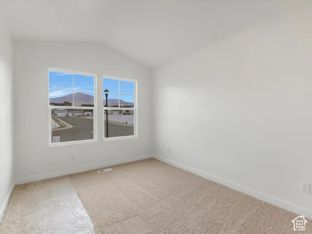 Carpeted flooring, vaulted ceiling, and two large windows offering abundant natural light