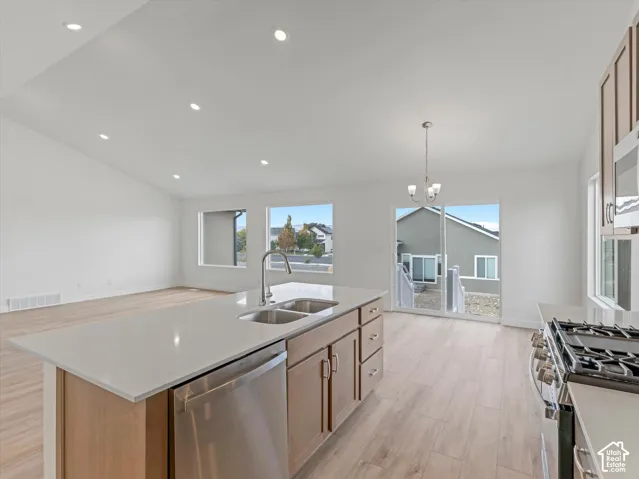 Vaulted ceiling with recessed lighting, kitchen island with double sink, stainless steel appliances, wood-finish flooring, and sliding glass door