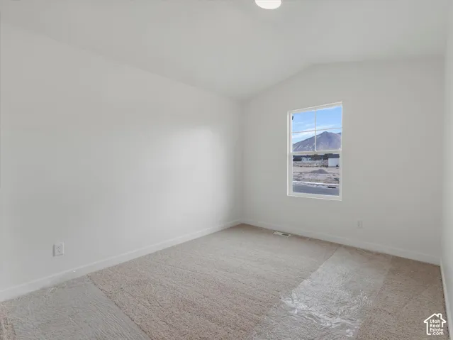Vaulted ceiling, recessed lighting, neutral carpeting, double-hung window, and mountain scenery