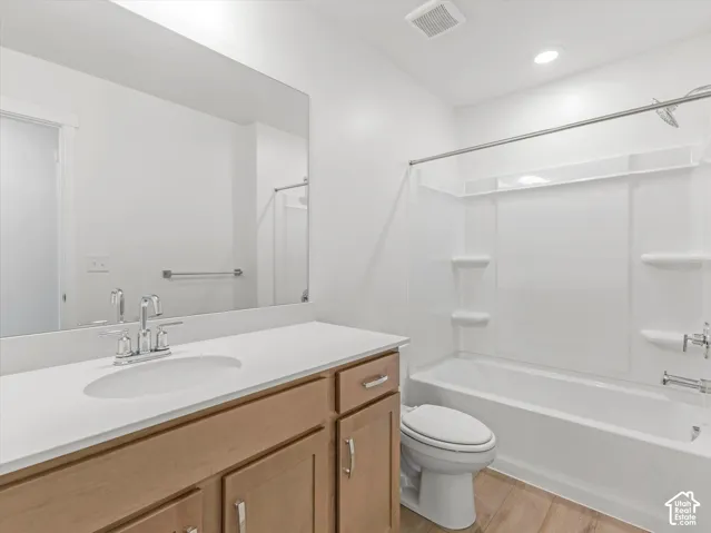 Bathroom featuring a wood-finish vanity with an integrated sink, polished chrome faucet, and a large wall-mounted mirror