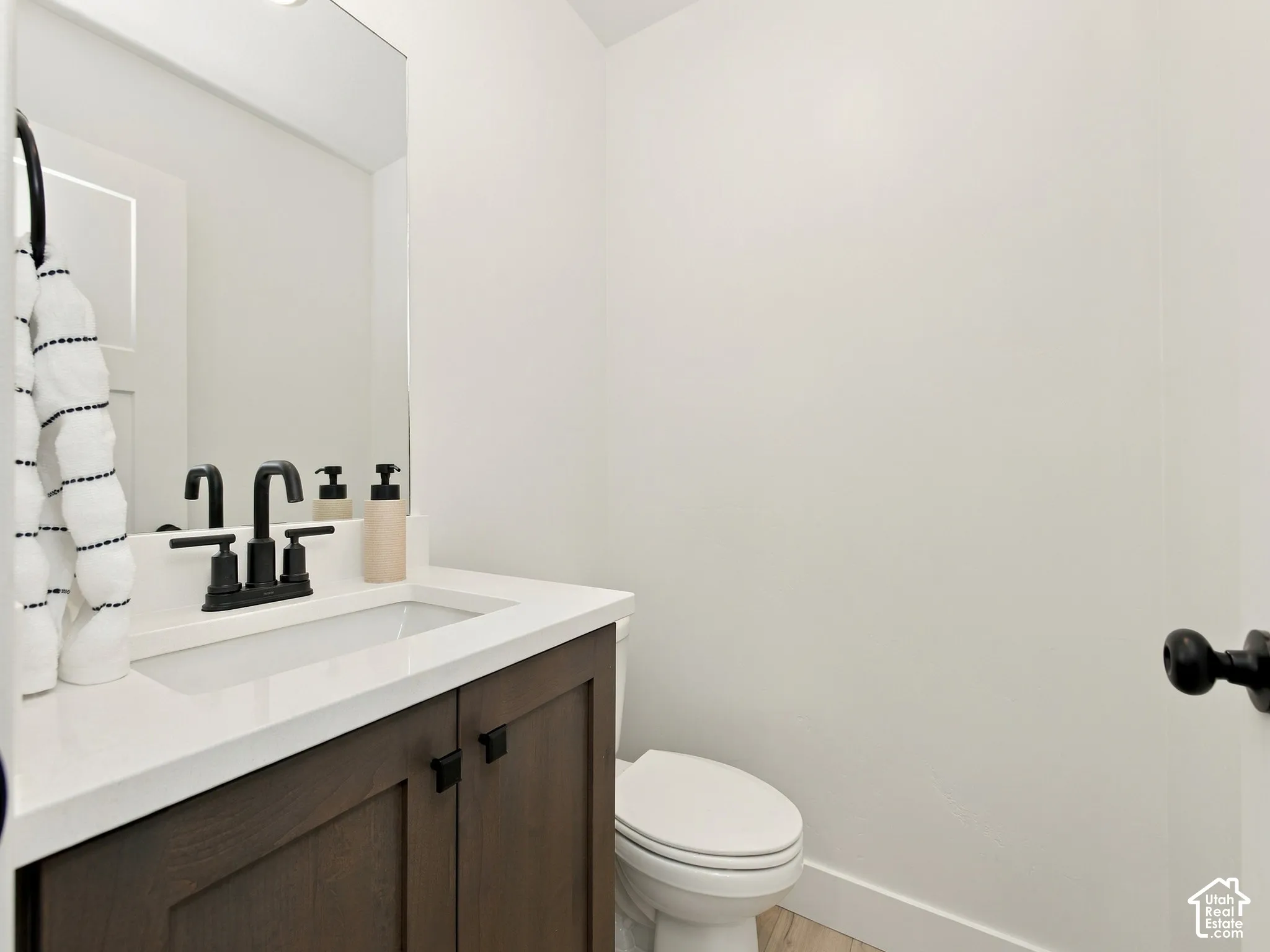 Powder room featuring a single vanity with wood-finish cabinetry, a white countertop, and a rectangular undermount sink
