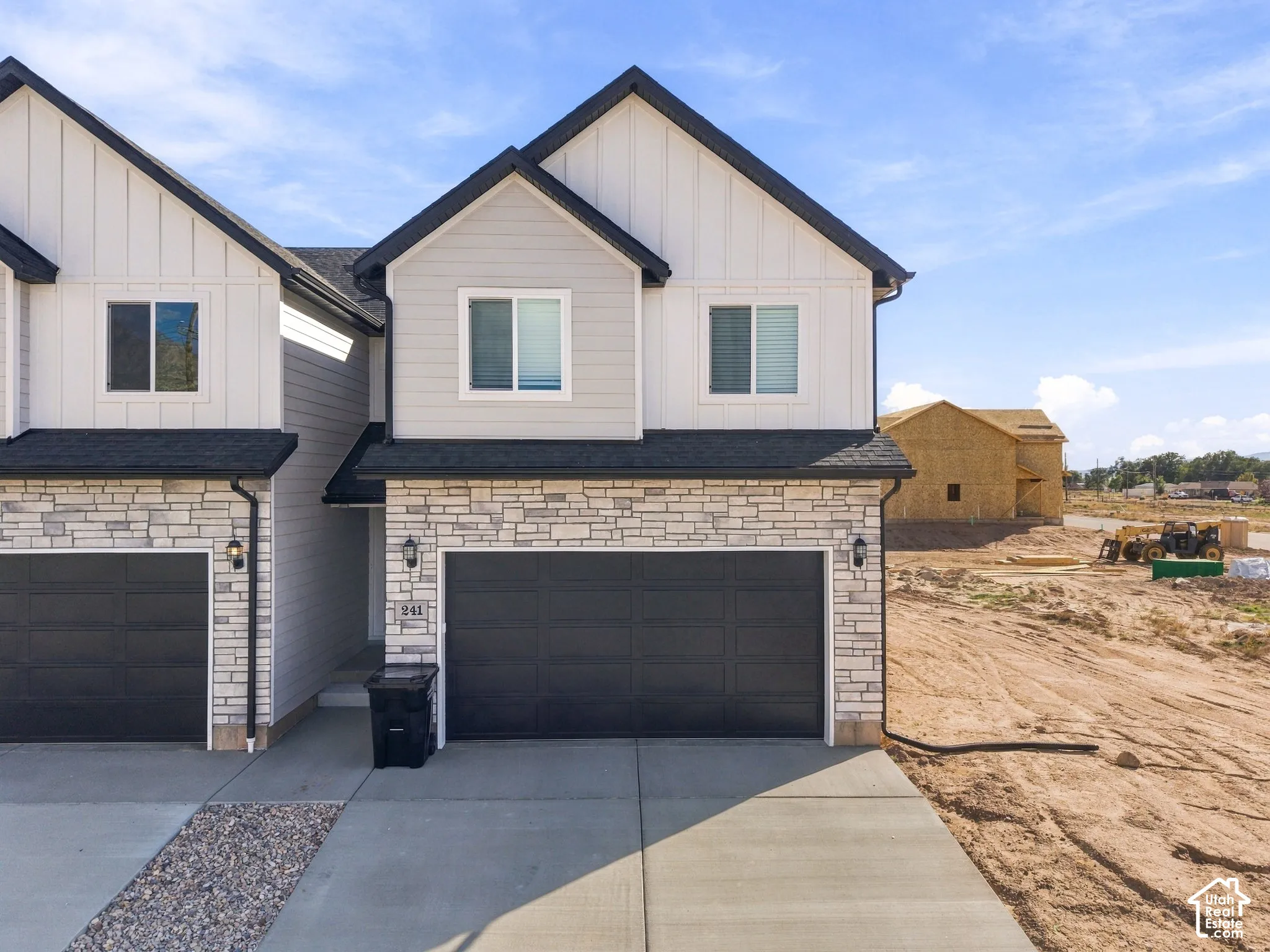Modern exterior design featuring light-toned stacked stone, vertical siding, and contrasting dark trim