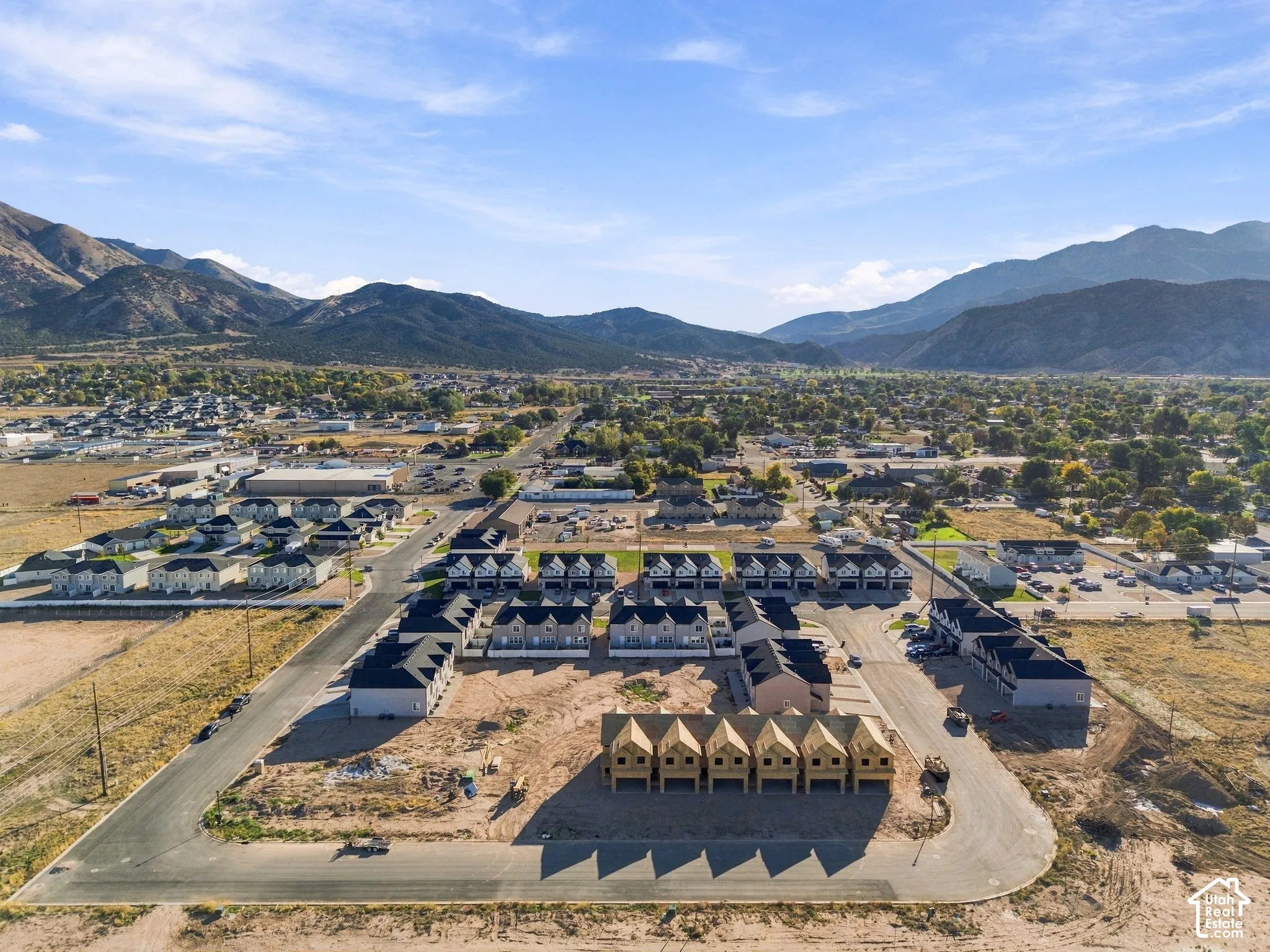 New construction development with multiple residential structures, paved roads, and mountain scenery