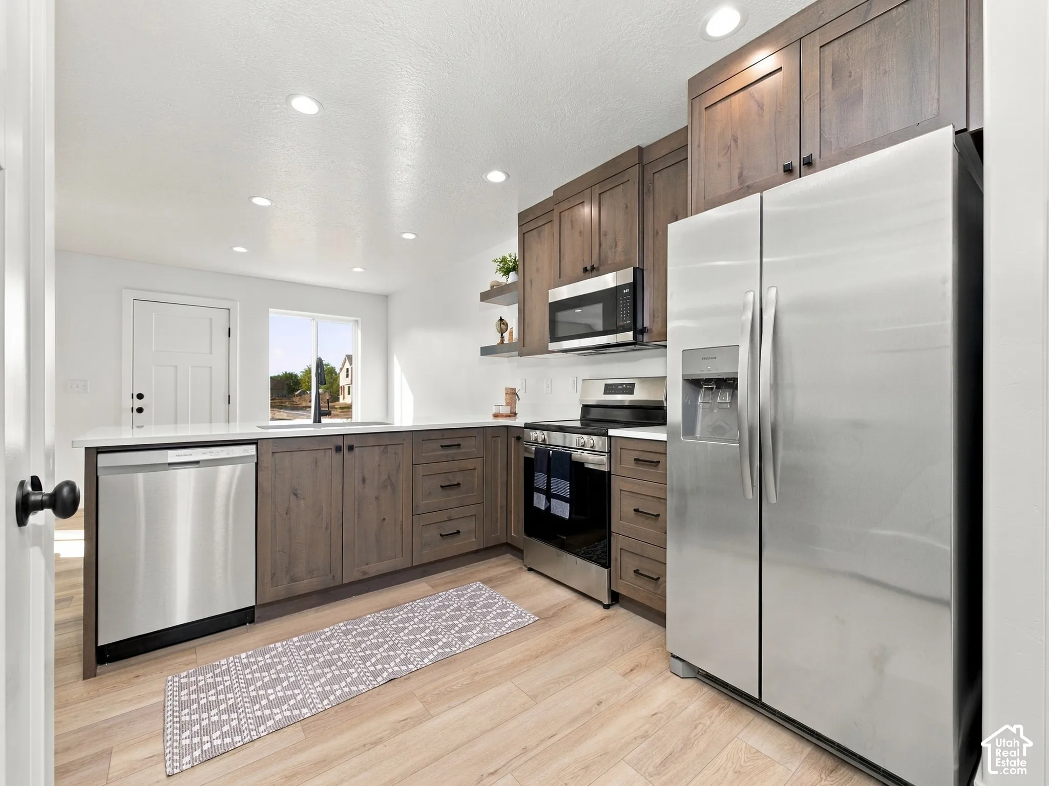 Kitchen featuring wood-finish cabinetry, stainless steel appliances, recessed lighting, and wood-finish flooring