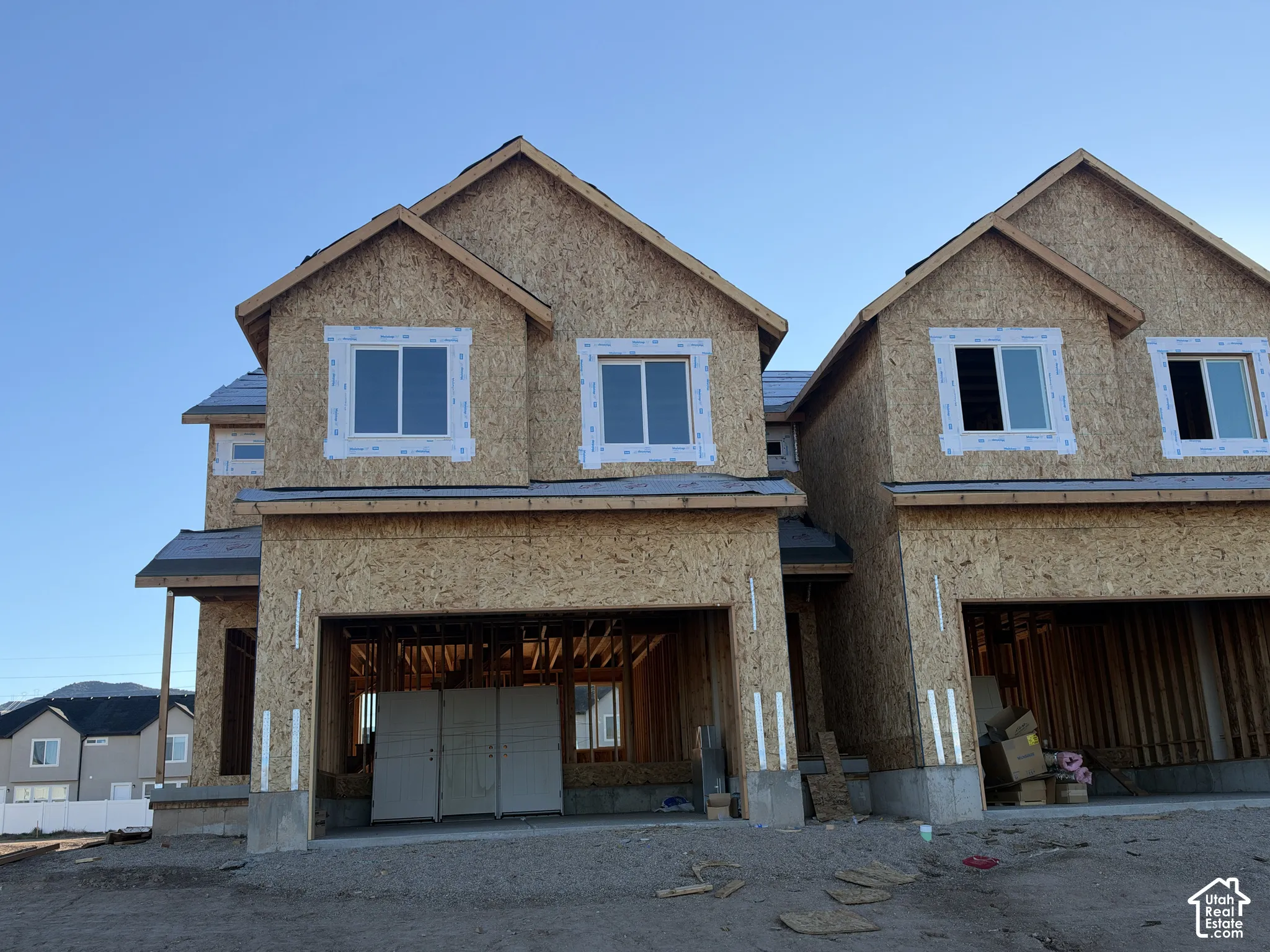 New construction exterior featuring oriented strand board sheathing, multi-gable rooflines, and installed dual-pane windows
