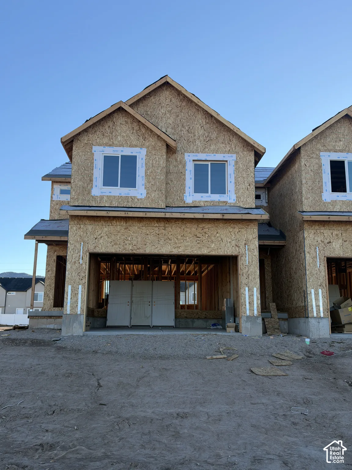 New construction multi-level residential structure featuring oriented strand board sheathing, gabled rooflines, double-pane vinyl windows, and a concrete foundation