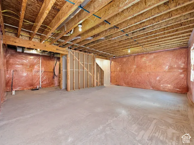 Unfinished basement with exposed ceiling joists, concrete flooring, and framed interior walls