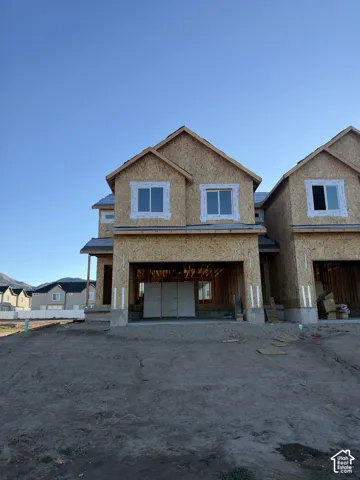 Multi-level residential exterior under construction featuring oriented strand board (OSB) sheathing, white-trimmed windows, a covered entryway, and a concrete foundation