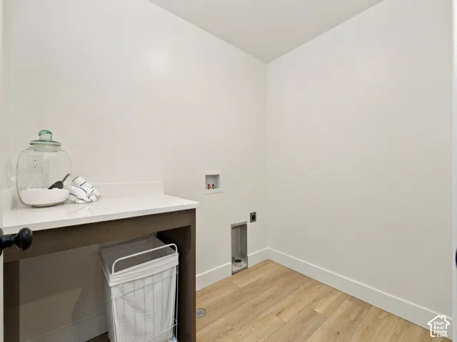 White walls with light wood-finish flooring, featuring a built-in counter with a white surface