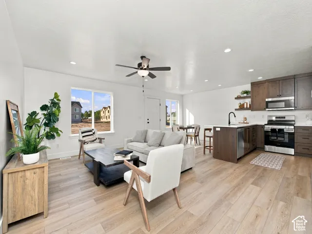 Open-concept living space featuring wood-finish flooring, recessed lighting, and a ceiling fan