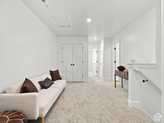 Recessed lighting, light-toned carpeting, white interior doors, and a white handrail with black iron newel