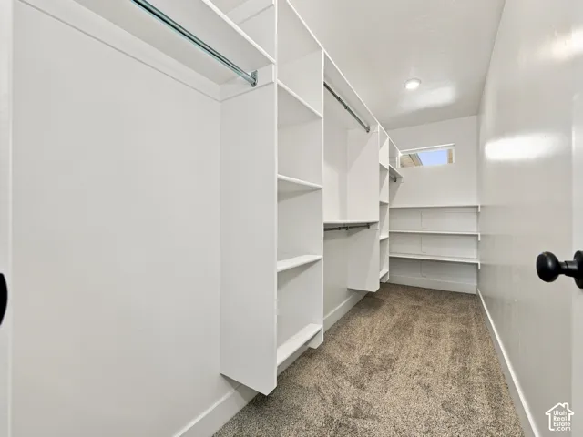 Walk-in closet featuring extensive built-in shelving, multiple hanging rods, recessed lighting, and a high-set window