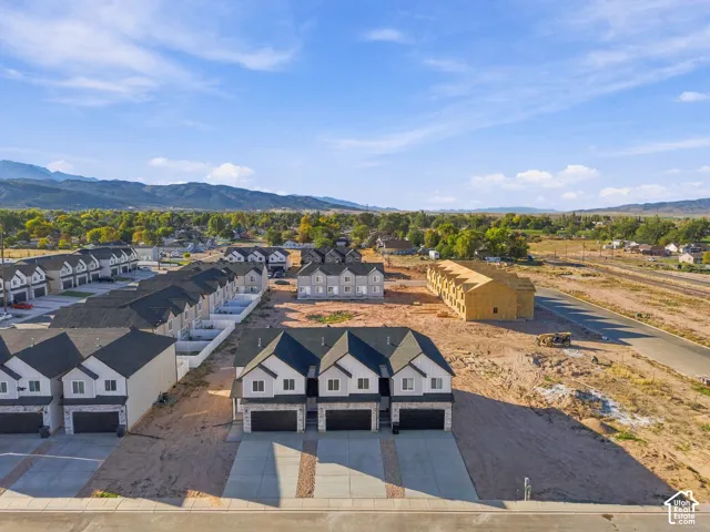 Newly constructed townhomes with attached garages, concrete driveways, stone accents, and durable asphalt shingle roofing