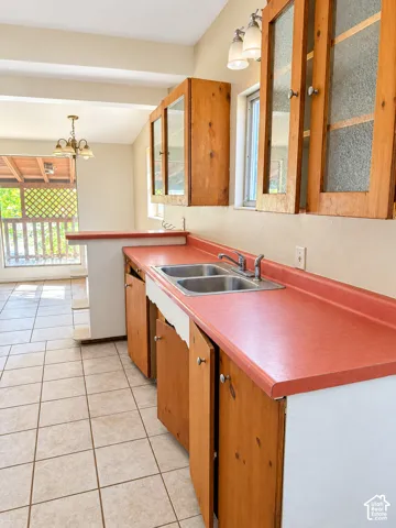 Kitchen featuring a dual basin sink, light wood cabinetry, and tiled flooring